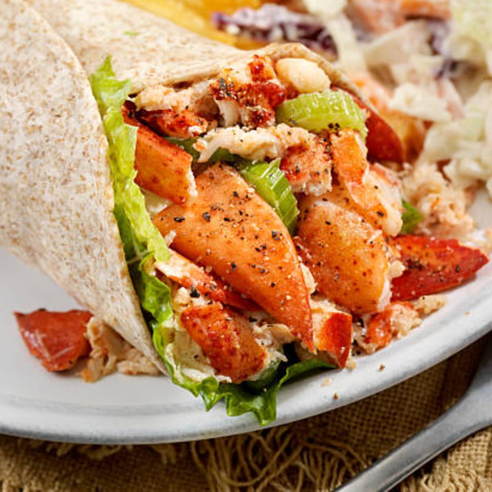 Boston Seafood Company's lobster wrap with fresh lettuce, celery, and seasoning on a white plate.